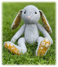 a gray stuffed animal sitting on top of a lush green grass covered field with white flowers