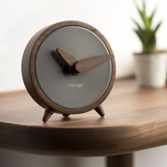 an alarm clock sitting on top of a wooden table next to a potted plant