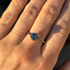 a woman's hand with a ring on it and a blue stone in the middle