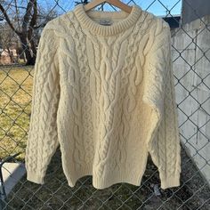 a white sweater hanging on a chain link fence