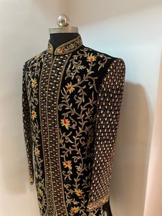 a mannequin is dressed in black with gold and red flowers on the back