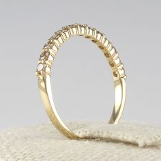 a yellow gold wedding ring with three rows of diamonds on the top and bottom, sitting on a white cloth