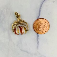 "This is a beautiful Victorian style Swivel Fob Seal / Pendant in 9K / 9ct yellow gold. The spinning fob pendant features hand carved floral gold design and a triangle shaped banded agate with vibrant white, red/orange, and yellow colors. The fob measures 0.87\" (22.3mm) high including bail without split ring and 0.76\" (19.4mm) wide at it is widest point. It is fully hallmarked for Birmingham Assay, 9ct gold, and year letter for 1977. It weighs 3.862 grams. All of our listings come in a box rea Yellow Gold Oval Agate Jewelry, Gold Agate Jewelry With Polished Finish, Oval Agate Yellow Gold Jewelry, Oval Yellow Gold Agate Jewelry, Gold Cabochon Agate Jewelry, Gold Agate Cabochon Jewelry, Collectible Yellow Gold Jewelry With Oval Cabochon, Gold Agate Hallmarked Jewelry, Antique Miniature Gold Jewelry