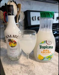 two bottles of tropicana and a wine glass on a kitchen counter top