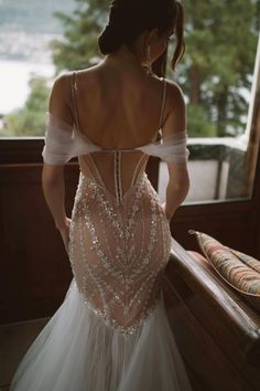 a woman in a wedding dress looking out the window