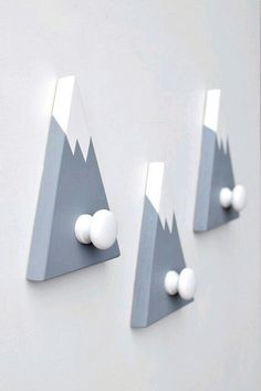 three white balls are stuck to the side of a gray and white wall with mountains on it