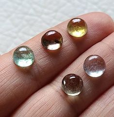 three different colored stones sitting on top of a person's finger