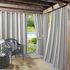 a living room filled with furniture next to a window covered in gray drapes and curtains