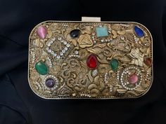 a gold colored purse with colorful stones on it