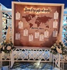 a wedding display with seating cards attached to the wall and flowers in front of it