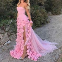 a woman wearing a pink dress with flowers on the side and her legs slited up