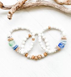 Such a beautiful easy breezy beach stack! Bracelets #1 & #2 are made with matte white Ghana glass beads and African recycled glass beads along with bone and coconut shell. Bracelet #3 is made of white turquoise and bone. Each bracelet is sold separately. Use the drop down bar to select one, two or all three  bracelets. Thank you for looking!  PLEASE NOTE, I need your wrist size not your bracelet size.  How to measure your wrist:  take a piece of string or ribbon (not any other cord) wrap it around the largest part of your wrist then lay it on a ruler or tape measure and that's your wrist size. White Hand-strung Bracelets For Beach, White Adjustable Stretch Bracelet With Beachy Style, Adjustable White Stretch Bracelet With Beachy Style, White Adjustable Beachy Stretch Bracelet, White Hand-strung Beaded Bracelets For Beach, White Hand-strung Beaded Bracelet For Beach, White Beaded Beachy Bracelet, Bohemian Turquoise Stretch Bracelet With Heishi Beads, Bohemian Turquoise Heishi Beads Stretch Bracelet