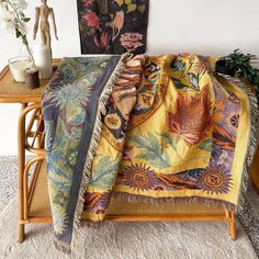 a bed with a blanket on top of it next to a vase filled with flowers