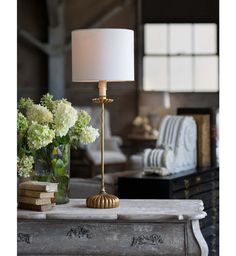 a lamp sitting on top of a table next to a vase with flowers in it