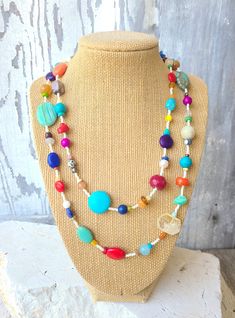 "Two pretty graduated strands of multi-color, semi precious stones make up this semi precious stone necklace.  Just about every stone you can imagine, turquoise, garnet, lapis lazuli, pearls, chrysoprase, red coral, and carnelian, just to name a few. In between the stones are cream/gold color Japanese seed beads. The necklace measures 18\" on the shortest length and 22\" on the longest length. Both  strands are connected with a large silver toggle clasp.  It is strung on an 18 strand nylon coate Bohemian Rainbow Necklaces With Natural Stones, Bohemian Rainbow Beaded Necklaces With Natural Stones, Bohemian Rainbow Beaded Necklace With Natural Stones, Colorful Beaded Necklaces With Natural Stones, Colorful Natural Stone Beaded Necklaces With Round Beads, Bohemian Rainbow Gemstone Beaded Necklace, Colorful Bohemian Necklaces With Natural Stones, Multicolor Gemstone Beads Beach Jewelry, Multicolor Gemstone Beads Jewelry For Beach