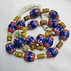 a multicolored bead necklace with white cords and beads on the clasps