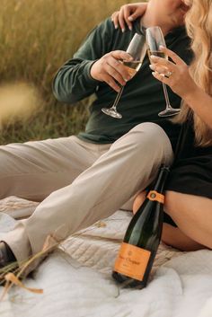 two people sitting on a blanket holding wine glasses