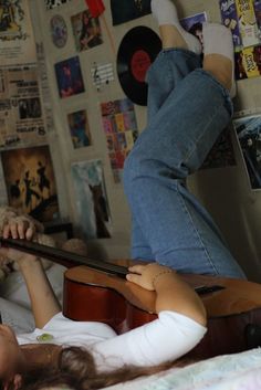 a woman laying on top of a bed next to a guitar