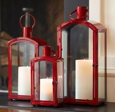 two red lanterns sitting next to each other on top of a mantle filled with candles