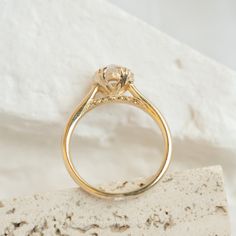 a yellow gold engagement ring with a diamond on it's shants, resting on a rock