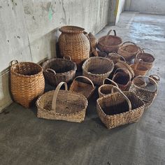 many baskets are lined up on the floor in front of a wall with concrete walls