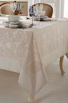 a dining room table with white linens and place settings