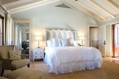 a large white bed sitting inside of a bedroom next to two lamps on either side of the bed