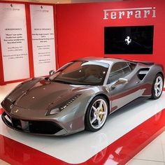 a silver sports car is on display in a showroom with red walls and white flooring