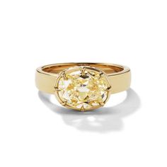 a yellow gold ring with an oval cut diamond in the center, on a white background