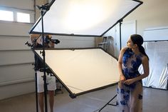 a woman is standing in front of a camera and lighting equipment while another person stands behind her