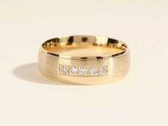 a yellow gold wedding ring with three diamonds on the inside and outside, sitting on a white surface