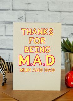 a card that says thanks for being mad mum and dad with a toy zebra next to it