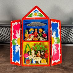 a brightly colored toy house with figurines in it's display case on a wooden table