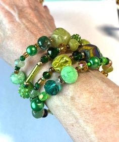 This green beaded bracelet wraps 4 times around the wrist.  It features a hand painted bead, two vintage wooden beads dating from a 1950s necklace, two olive green plastic beads from a 60's necklace, czech crystal beads in several shades of green, unique glass beads and some small vintage pearls.  It will match any green clothes you have because every hue of green possible is represented.  It is bling in a subtle way!