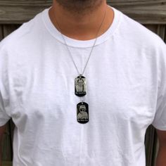 a man wearing a white t - shirt with two pendants on his chest,