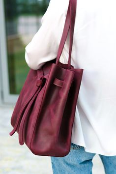 "The color in the first photo is matt sangria 💜 📌TOTE SIZING: LARGE 🖇️We can offer customized settings. Please see the description for each item. Ribbon drawstring bucket bag with long handles and spacious interior. This bag with long double handles, made of Ukrainian Pull Up leather, is a waxed leather with a distressed effect. At the top, the bag can be supplemented with a magnetic closure or hook, which keeps all your belongings securely. This carry bag is perfect for all your daily needs. Work Bags For Women, Purple Tote, Purple Tote Bag, Tote Bag With Pockets, Tote Bag Custom, Large Leather Tote Bag, Drawstring Bucket Bag, Large Leather Tote, Custom Tote Bags