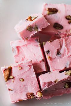 a white plate topped with pink fudge and nuts