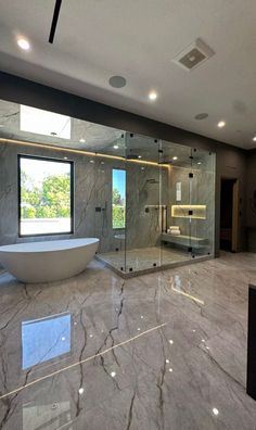 a large bathroom with marble flooring and glass shower walls, along with a freestanding tub