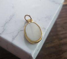 oval shaped mother of pearl with gold frame.  4mm jump ring pendant size 20x11mm Classic White Oval Pendant Jewelry, White Oval Pearl Pendant Jewelry, White Cabochon Mother Of Pearl Jewelry, White Cabochon Oval Pendant Jewelry, White Pearl Charm Jewelry, White Oval Jewelry With Pearl Charm, White Mother Of Pearl Cabochon Jewelry, Oval Pearl Drop Jewelry, Handmade White Jewelry With Oval Cabochon