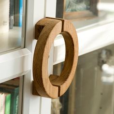 a close up of a wooden door handle on a window sill with books in the background