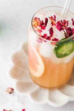 a drink in a glass with a straw and garnish on the rim, sitting on a white plate