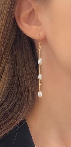 a close up of a woman's ear wearing gold earrings with pearls on them