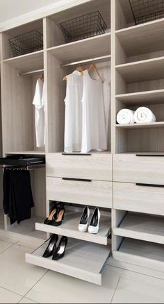 a walk in closet with white cabinets and black shoes