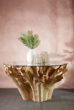 a glass table topped with a vase and a plant on top of a wooden stump