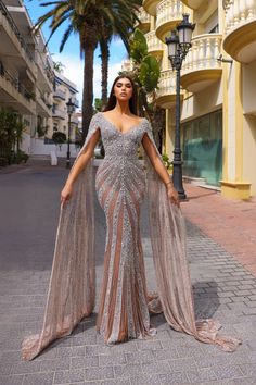 a woman standing on the street wearing a dress with long sleeves and an embellished cape