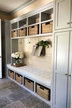 a room filled with lots of white and gray shelves next to a wall covered in baskets