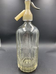 a clear glass bottle with a yellow plastic sprayer on it's head and handle