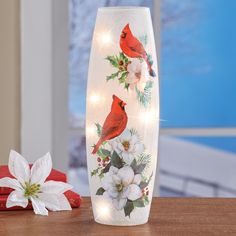 a lighted vase sitting on top of a wooden table next to a christmas ornament