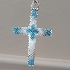 a blue and white beaded cross hanging from a chain