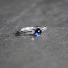 Do you need a gift for someone with a September birthday or to celebrate your 5th wedding anniversary? This sterling silver synthetic sapphire stacking ring is perfect if your birthstone is sapphire or you need a simple navy blue ring. Here are the details:This ring is made with either a rose cut (faceted) or smooth 5mm synthetic sapphire cabochon set in a sterling silver bezel and on a sturdy band handmade in your size. It can be worn with other stackable rings, or by itself.Please select your Blue Sapphire Stackable Rings For Anniversary, Dainty Bezel Set Sapphire Anniversary Ring, Minimalist Sapphire Birthstone Ring As Gift, Dainty Sapphire Ring With Bezel Setting For Anniversary, Minimalist Blue Sapphire Ring For Anniversary, Modern Sapphire Ring With Round Band, Blue Solitaire Birthstone Promise Ring, Blue Solitaire Birthstone Ring For Promise, Gift Sapphire Ring With Bezel Setting